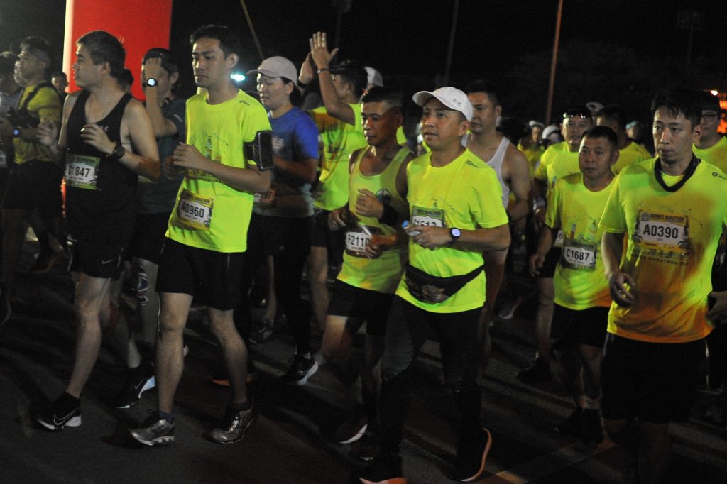 Runners crossing the starting line at Borneo International Marathon with vibrant crowd support