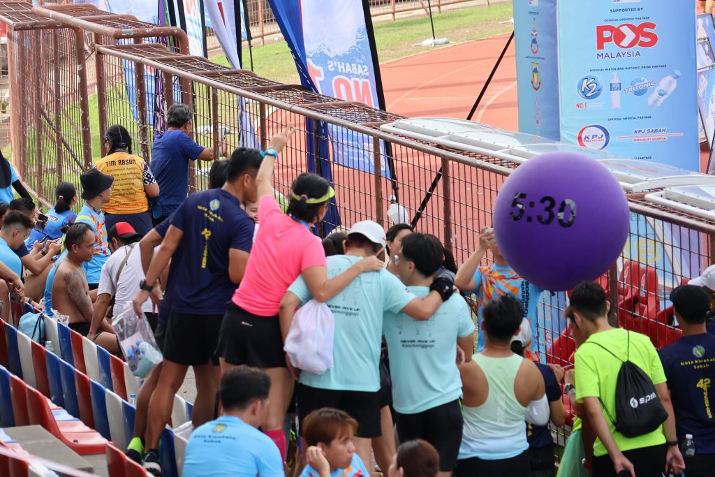 Family cheering with handmade signs at Borneo International Marathon sidelines