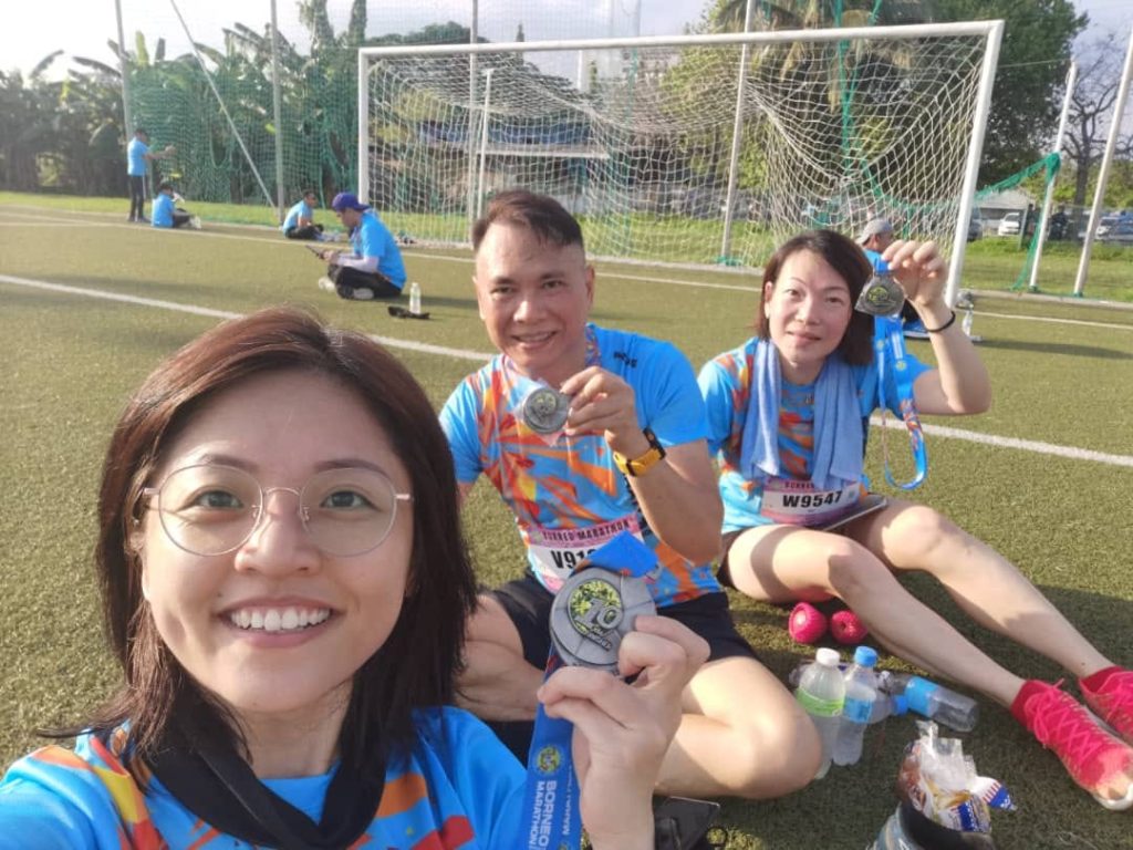 Exhausted but smiling marathon finisher receiving medal at Borneo International Marathon
