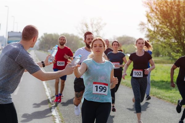 A runner drinking from an aid station during a marathon.