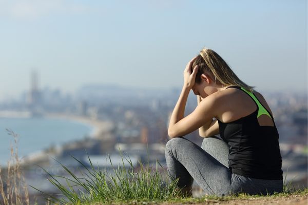 A runner looking frustrated after an injury, highlighting the importance of recovery in training.