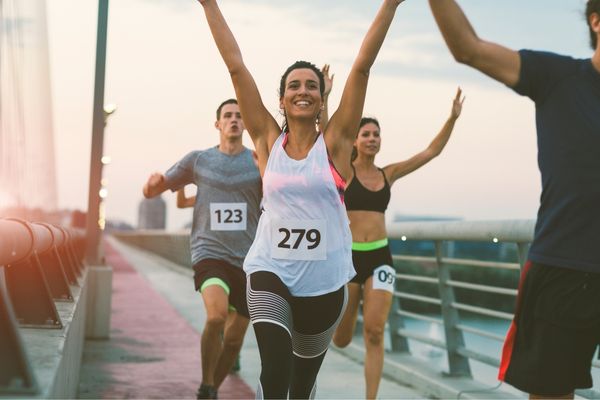 A runner gesturing while talking to attentive fellow runners.