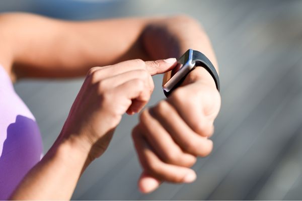 A runner checking their smartwatch for running stats.