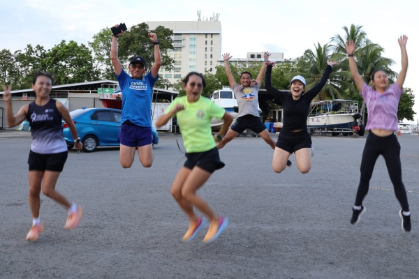 Marathon runners jumping and celebrating at the finish line in a joyful moment.