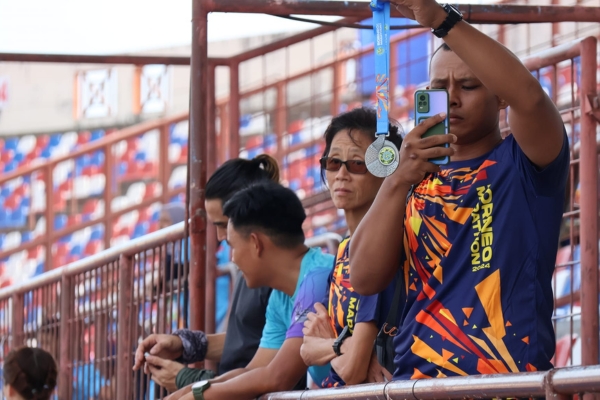 A close-up of a proud runner holding up their Borneo Marathon 2025 finisher medal.