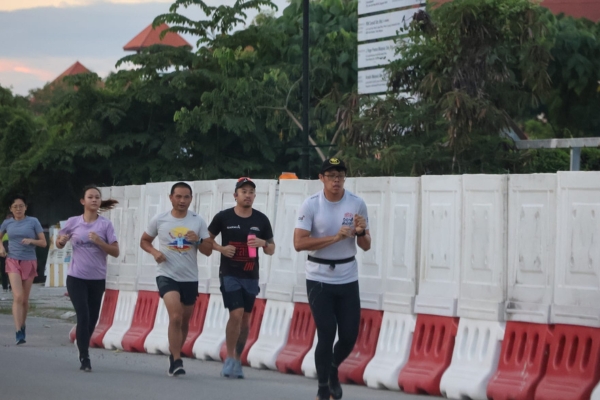 A group of focused runners jogging along a quiet morning trail in Borneo.