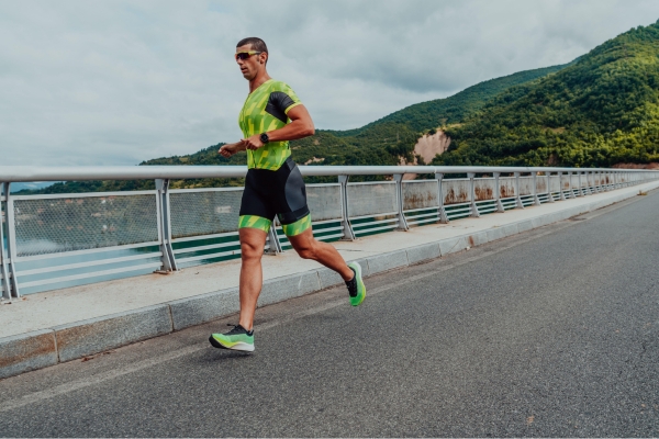Man in athletic gear running outdoors on a road with mountains and water, training for Borneo International Marathon.