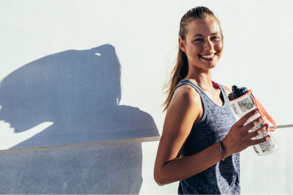 Marathon trainee practicing mid-run fueling strategy with gels and water