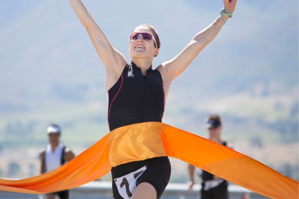 Runner crossing the finish line of a marathon with arms raised in victory